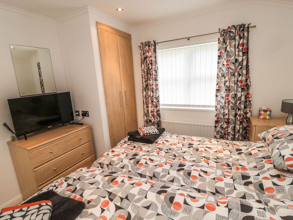 A bedroom with a bed and television at Nevaeh Lodge Longframlington