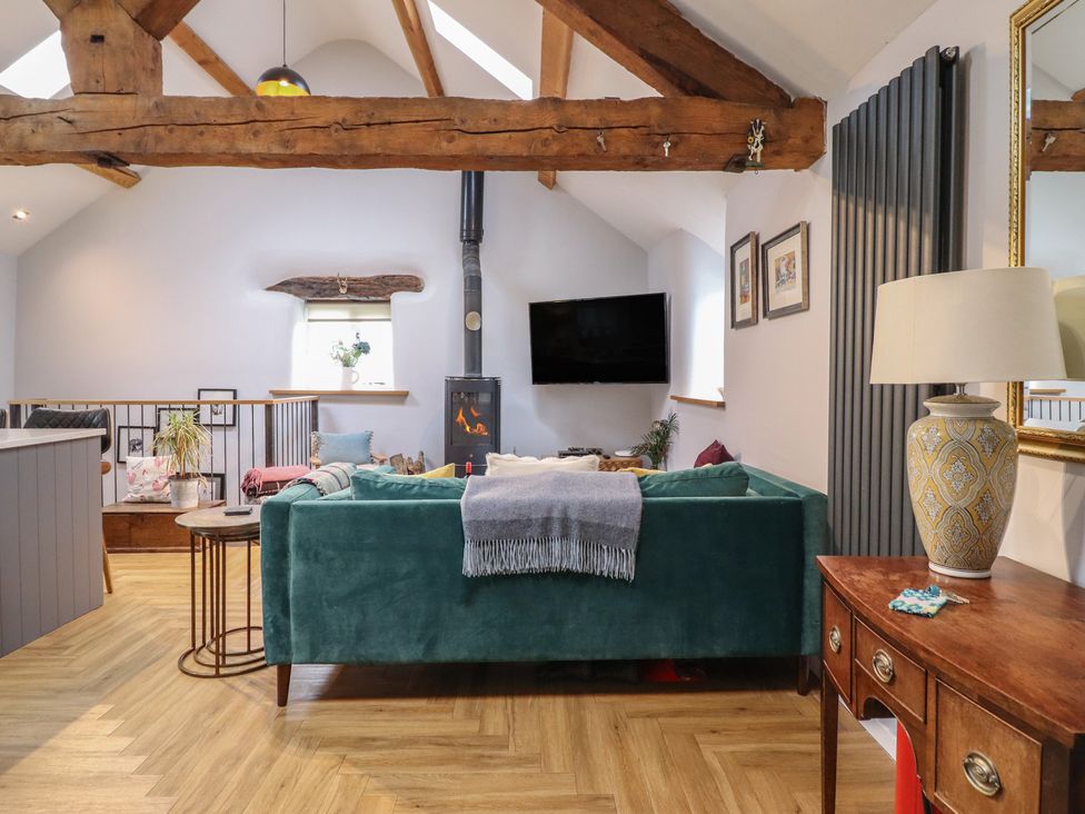 A living room with wooden beams and a television at The Old Cartshed | Yr Hen Gwt Cart in Abergele