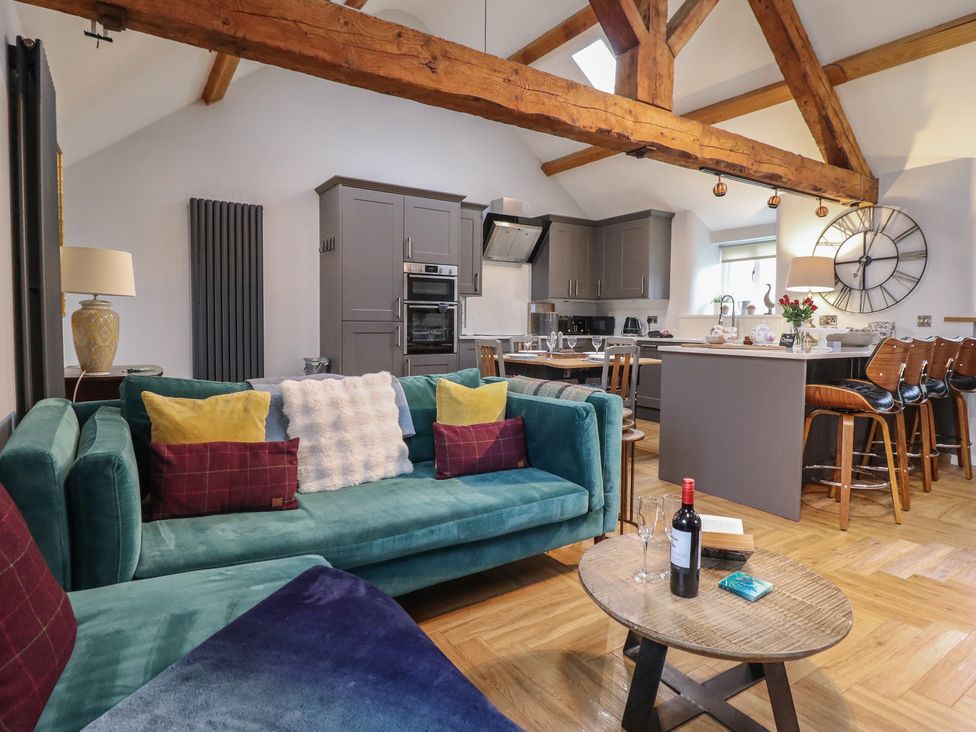 A living room with a sofa and kitchen area at The Old Cartshed | Yr Hen Gwt Cart Abergele