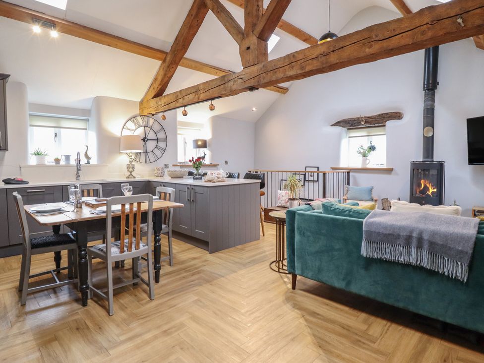 A living room with a dining table and a kitchen island at The Old Cartshed | Yr Hen Gwt Cart Abergele