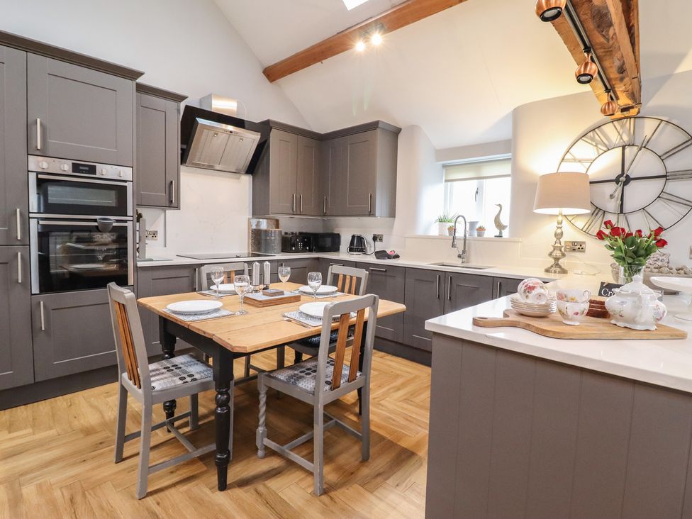 A kitchen with a dining table and chairs at The Old Cartshed | Yr Hen Gwt Cart in Abergele