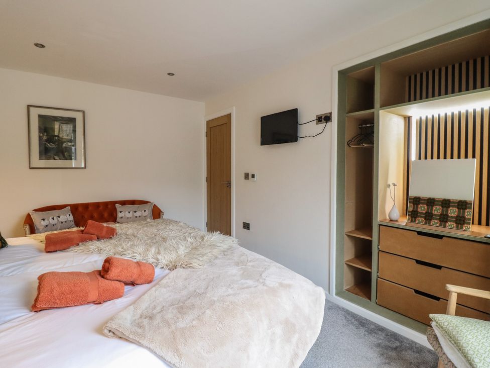 A bedroom with two beds and a television at The Old Cartshed | Yr Hen Gwt Cart, Abergele