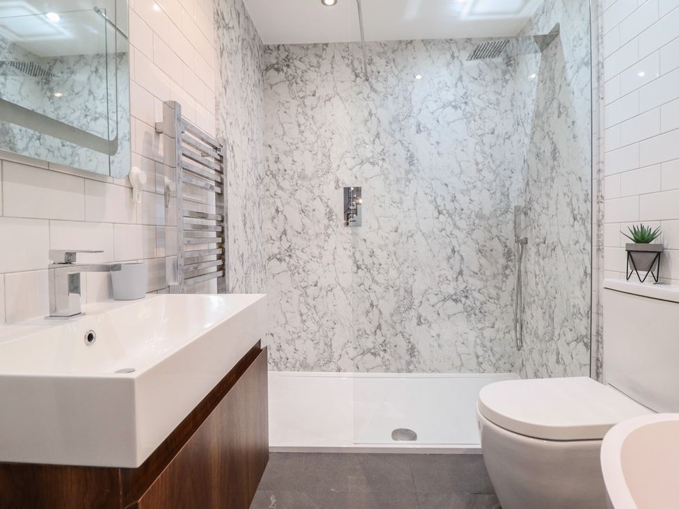 A bathroom with sink, toilet, shower, and wall-mounted mirror at The Old Cartshed | Yr Hen Gwt Cart, Abergele