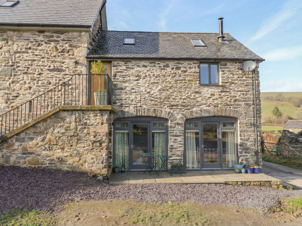 An outdoor area with a stone wall and seating at The Old Cartshed | Yr Hen Gwt Cart in Abergele