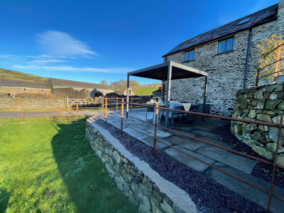 An outdoor area with a patio and seating at The Old Cartshed | Yr Hen Gwt Cart in Llangernyw