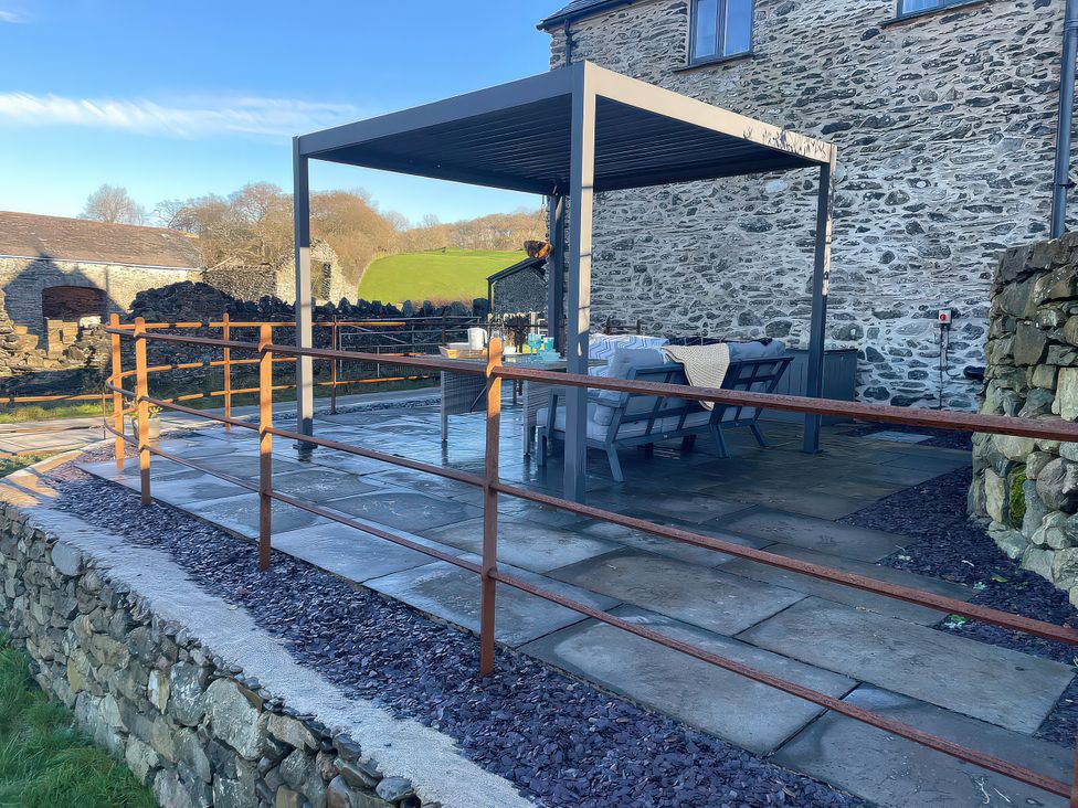 An outdoor area with a pergola and seating at The Old Cartshed | Yr Hen Gwt Cart in Llangernyw
