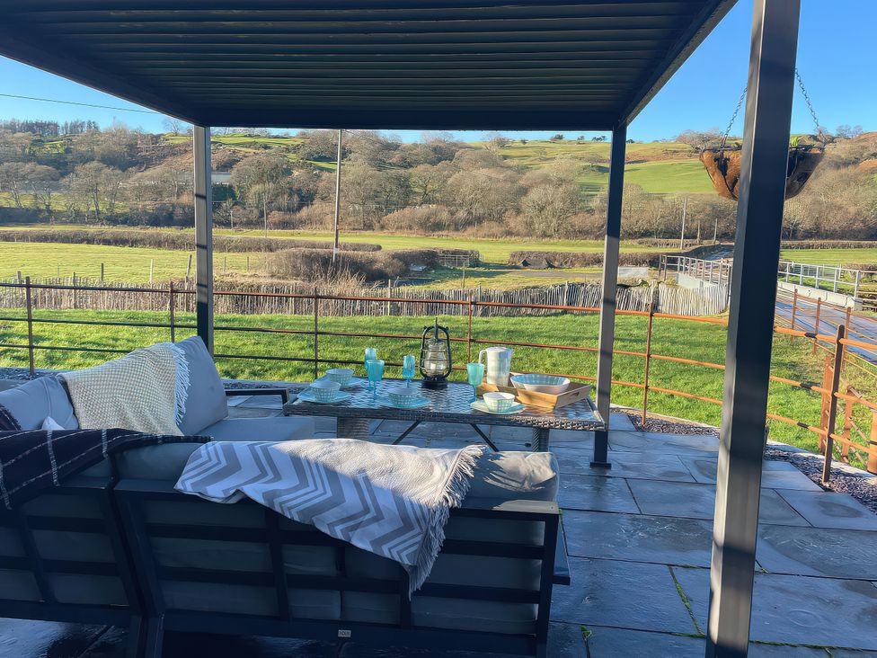 An outdoor patio with a sofa and table at The Old Cartshed | Yr Hen Gwt Cart, Llangernyw