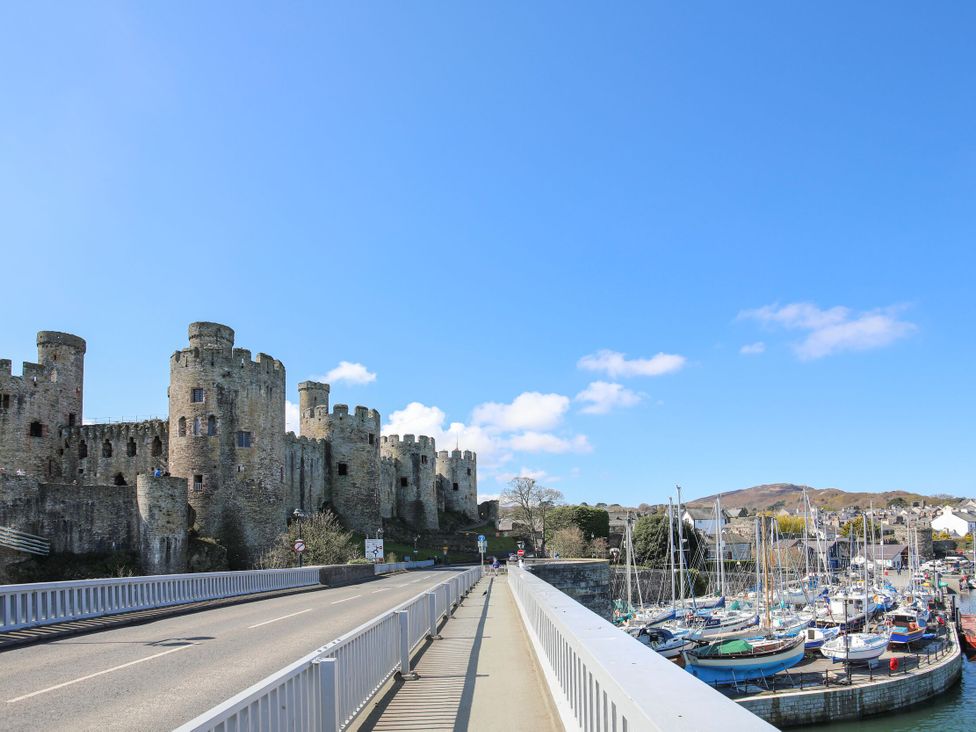 A view of a castle and marina with boats at The Old Cartshed | Yr Hen Gwt Cart in Llangernyw