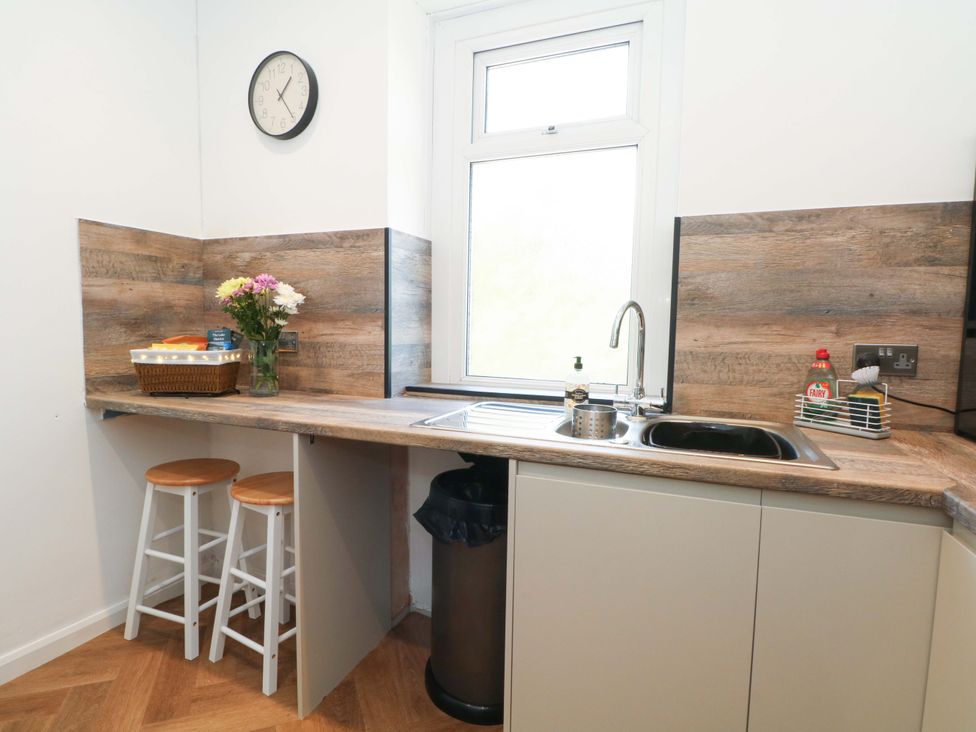 A kitchen with a sink and bar stools at 4 Newton Terrace in Lancaster