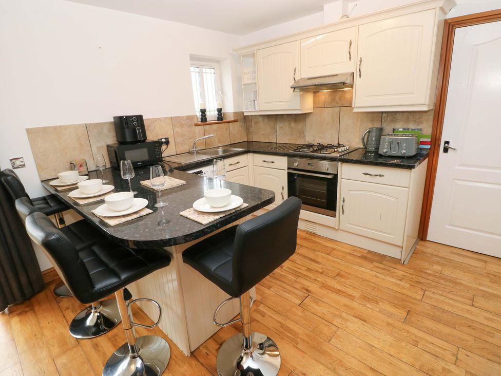 A kitchen with bar stools and appliances at Red Kite Cottage Haverfordwest