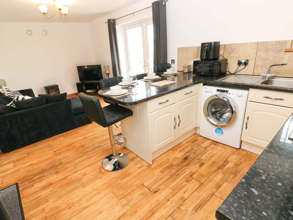 A kitchen with a washing machine and sofa at Red Kite Cottage in Haverfordwest