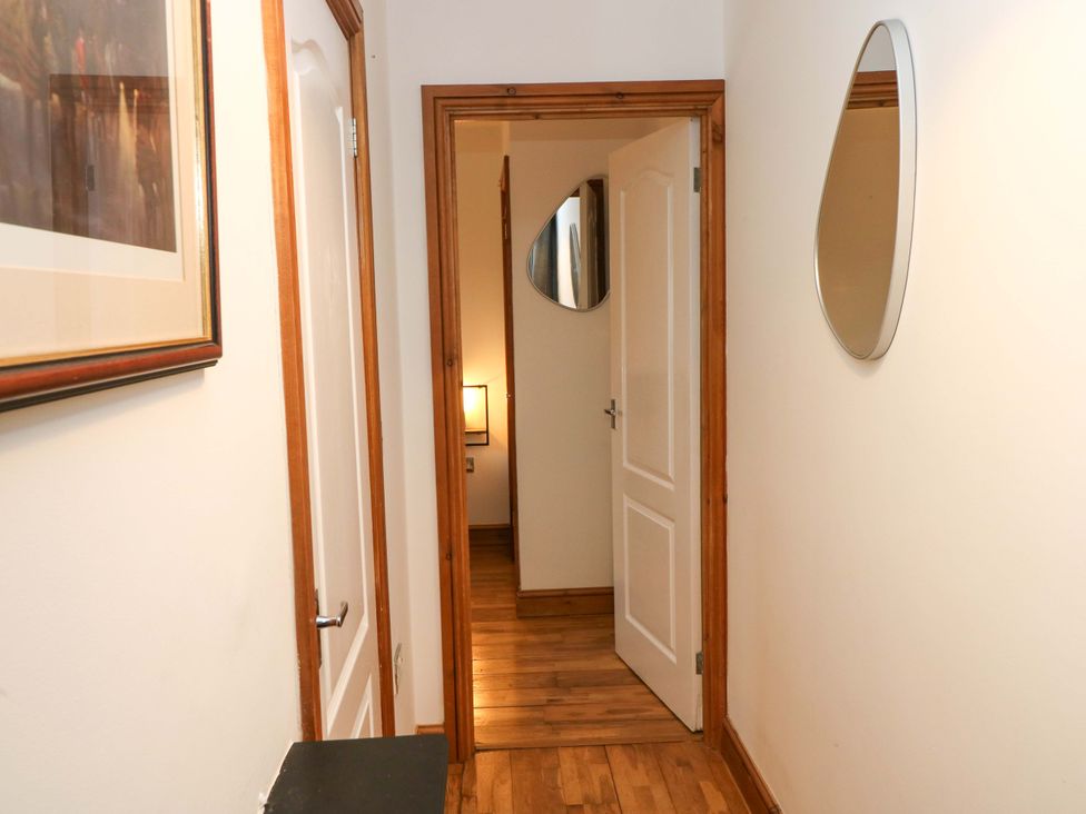 A hallway with a mirror and a door at Red Kite Cottage Haverfordwest