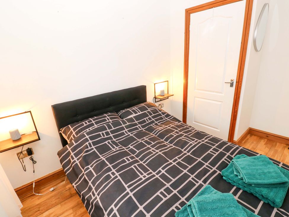 A bedroom with a bed, bedside lamp, and towels at Red Kite Cottage, Haverfordwest