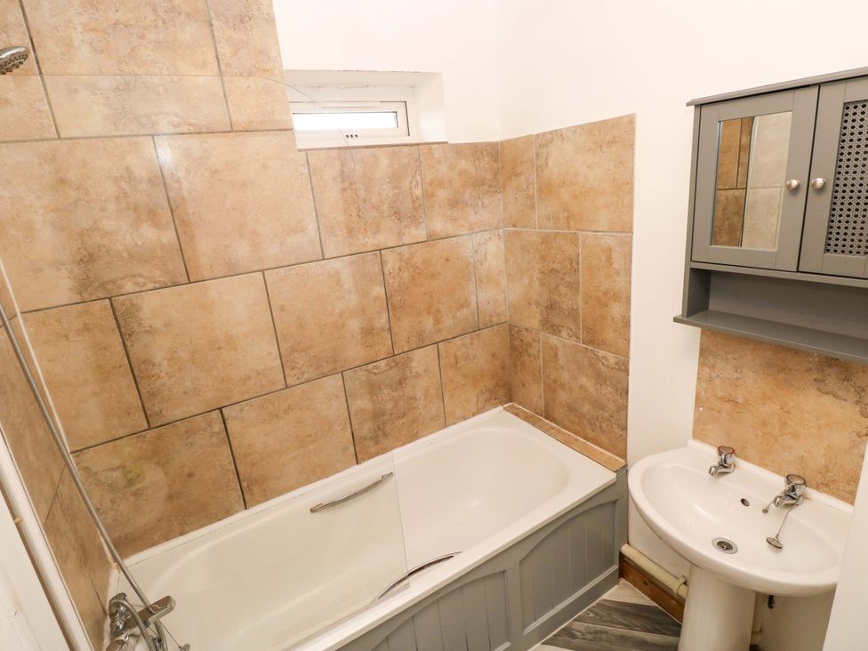 A bathroom with a bathtub and a wash basin at Red Kite Cottage Haverfordwest