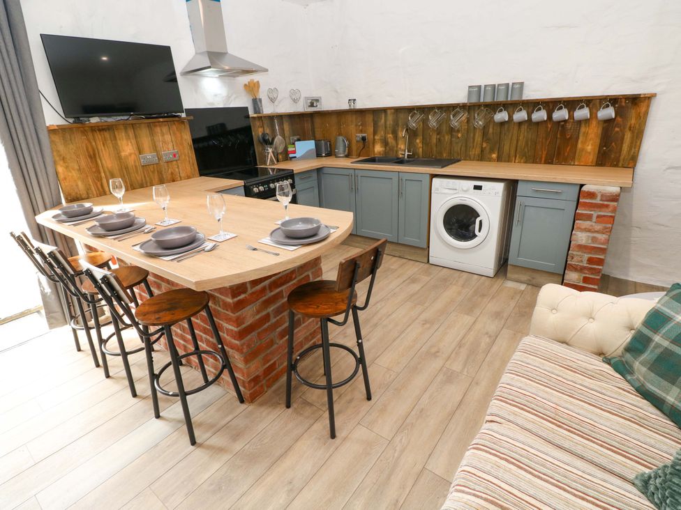 A kitchen with bar stools and appliances at Woodpecker in Haverfordwest
