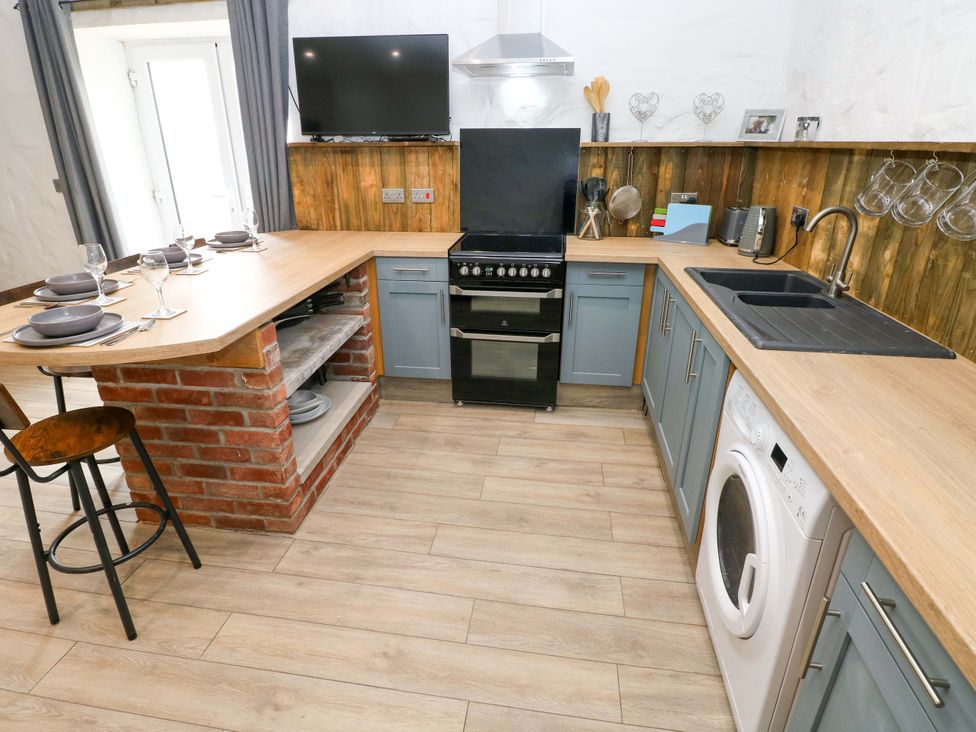 A kitchen with a stove and sink at Woodpecker in Haverfordwest