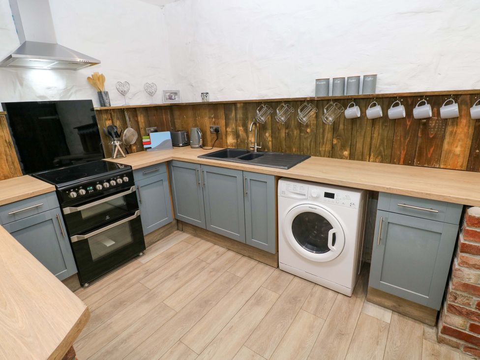 A kitchen with a stove, washing machine, and sink at Woodpecker in Haverfordwest