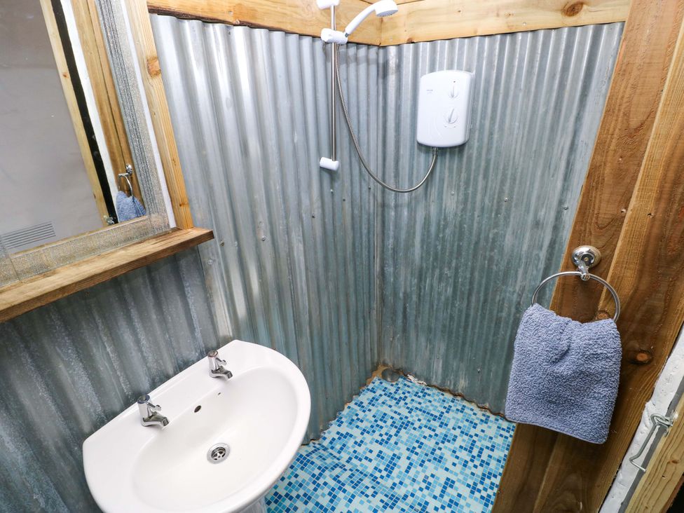 A bathroom with a shower and sink at Woodpecker in Haverfordwest
