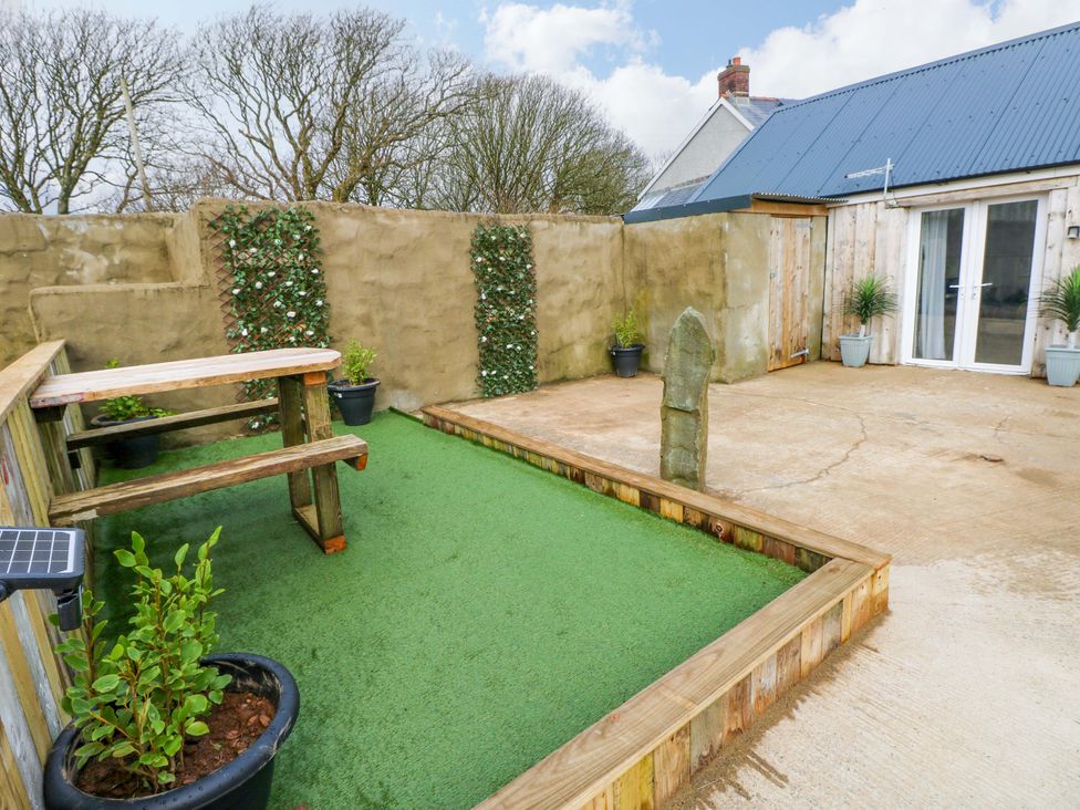 A garden with table, benches, planters, and artificial grass at Woodpecker in Haverfordwest