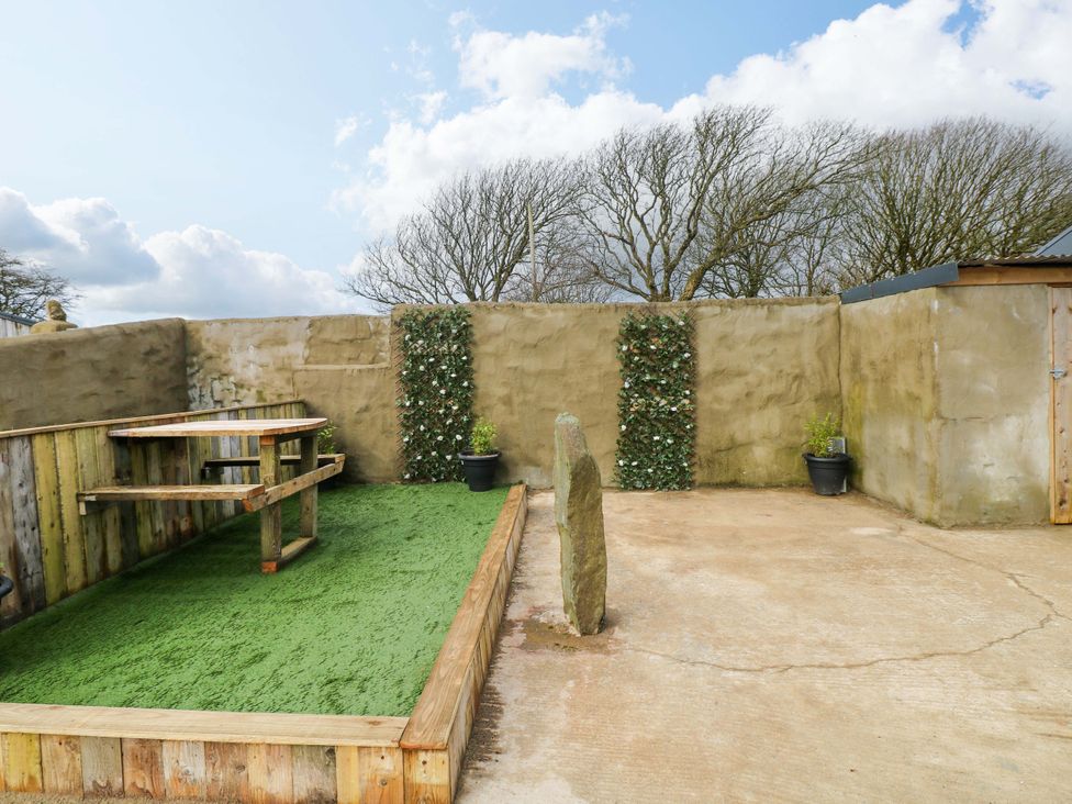 An outdoor area with wooden table and benches at Woodpecker in Haverfordwest