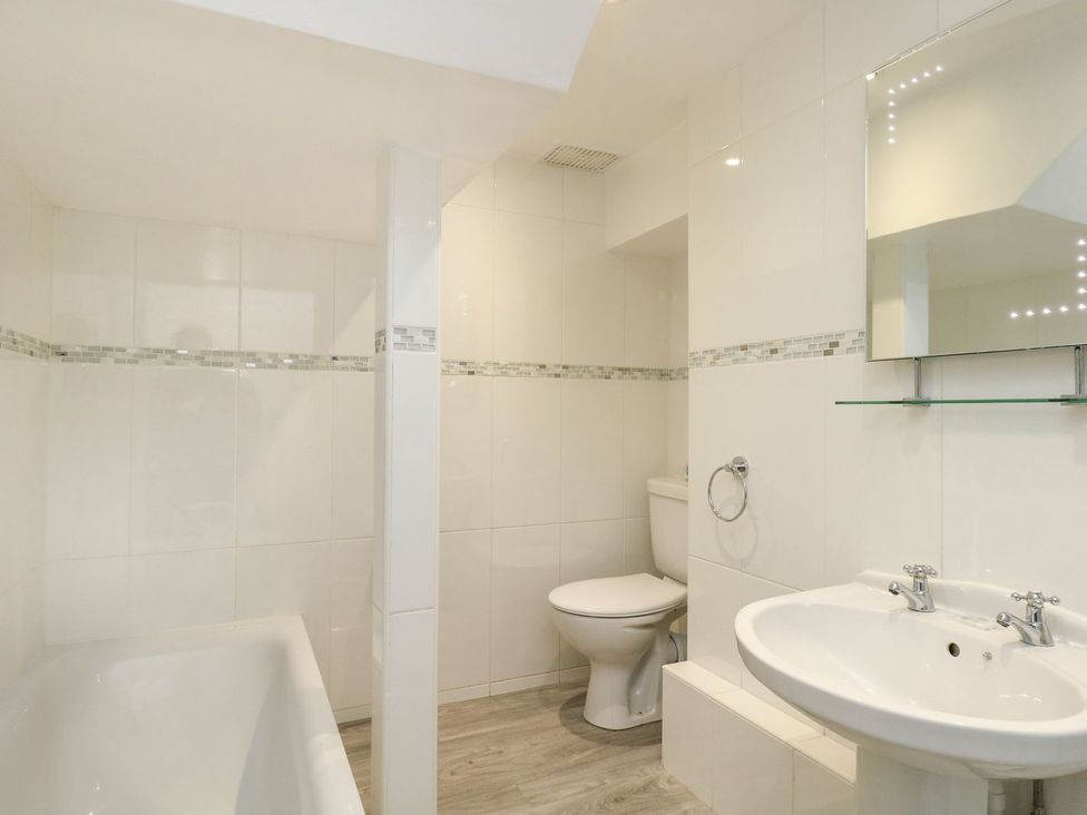 A bathroom with bathtub, toilet, and sink at Ocean Wave in Greenhill