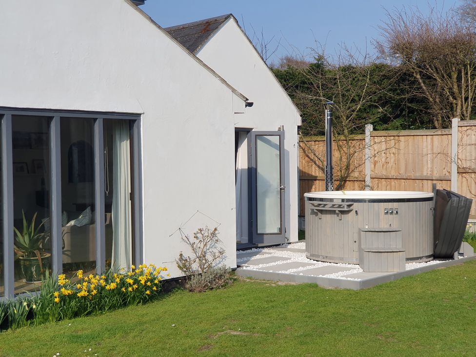 A garden with a hot tub and flower bed at Island Retreat in Colchester