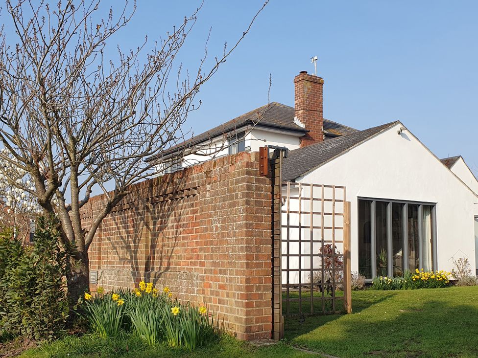 A garden with a brick wall and flowers at Island Retreat in Colchester