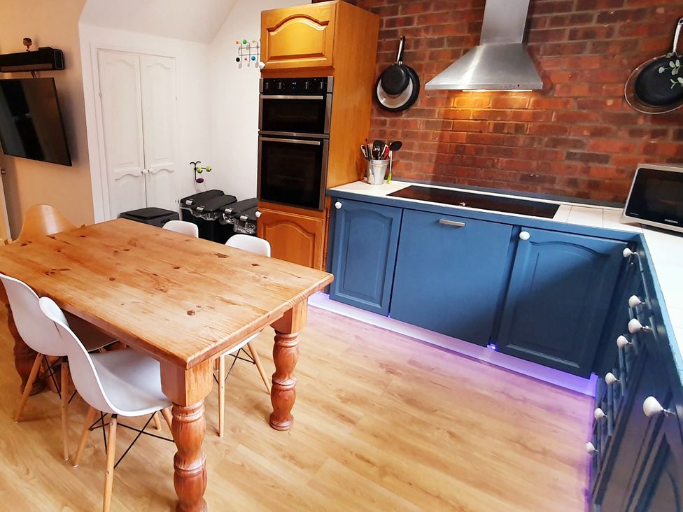 A kitchen with a wooden dining table and blue cabinets at Island Retreat in Colchester