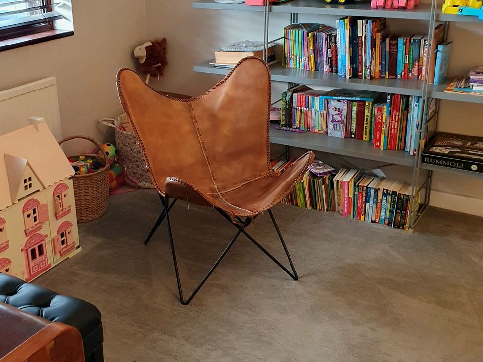 A playroom with a chair and bookshelf at Island Retreat in Colchester