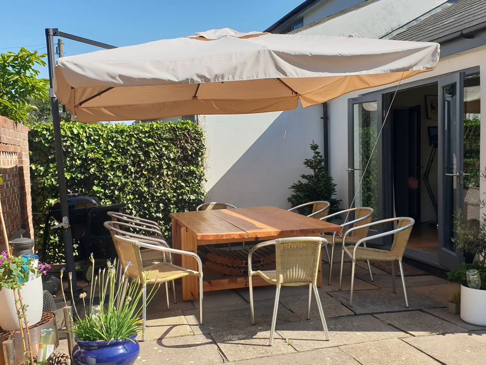 A garden with a wooden table and chairs under an umbrella at Island Retreat in Colchester