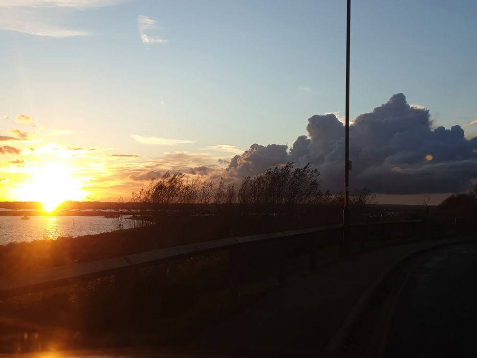 A sunset over water with clouds and a road at Island Retreat in Colchester