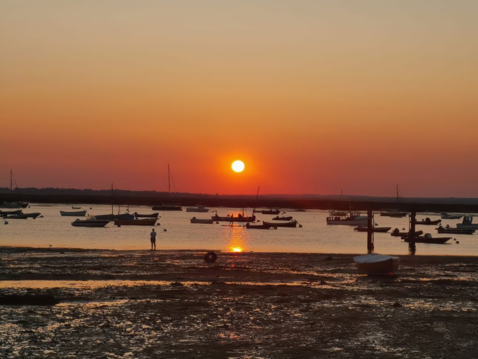 A sunset over a body of water with boats and a person at Island Retreat in Colchester