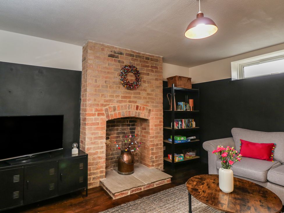 A living room with a television, bookshelf, and fireplace at Copper Cottage in Devizes