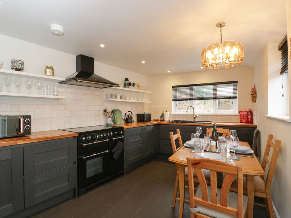 A kitchen with a dining table and stove at Copper Cottage in Devizes