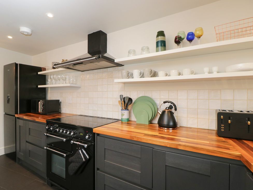 A kitchen with black appliances and wooden counters at Copper Cottage in Devizes