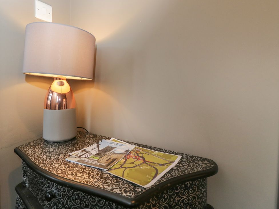 A lamp and magazines on a table at Copper Cottage in Devizes