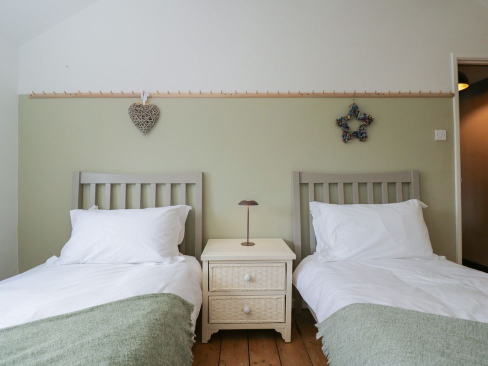 A bedroom with two beds and a bedside table at Copper Cottage in Devizes