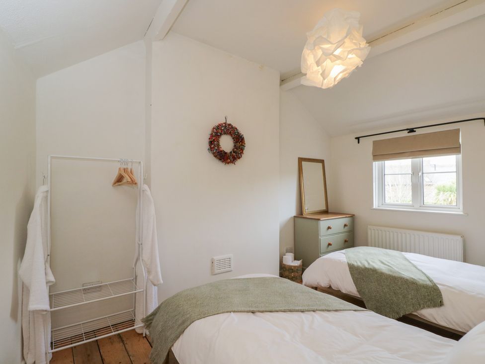 A bedroom with two beds and a shelf at Copper Cottage in Devizes