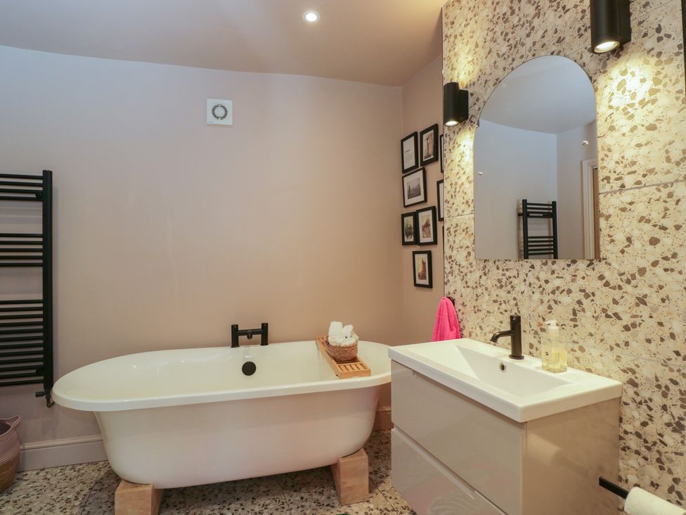 A bathroom with a bathtub, sink, and towel rack at Copper Cottage in Devizes