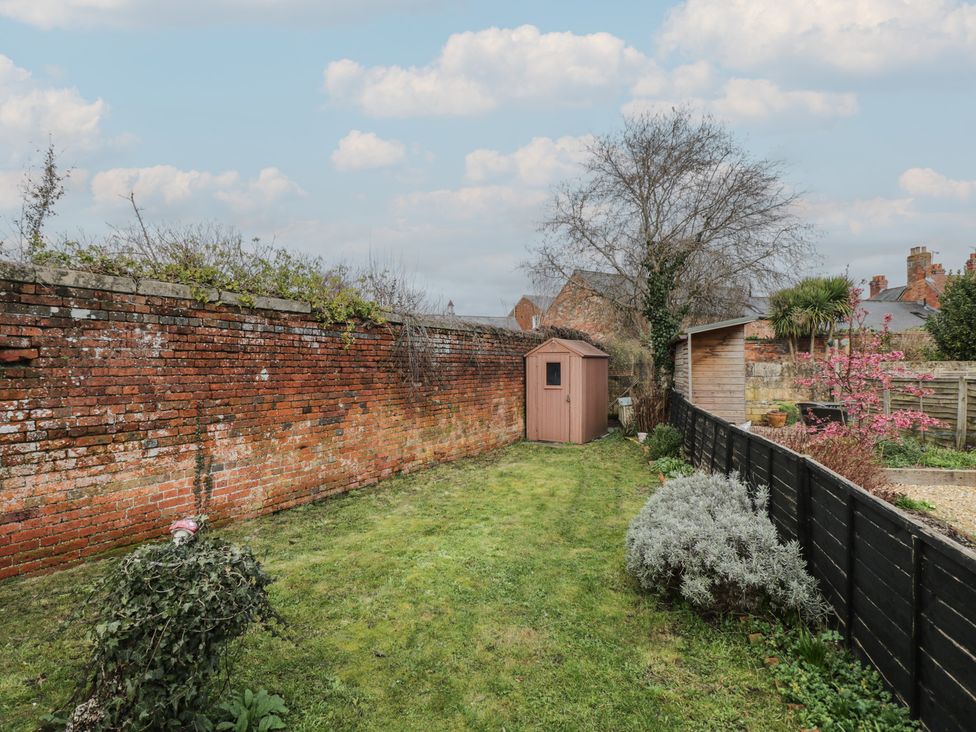 A garden with a shed and brick wall at Copper Cottage in Devizes