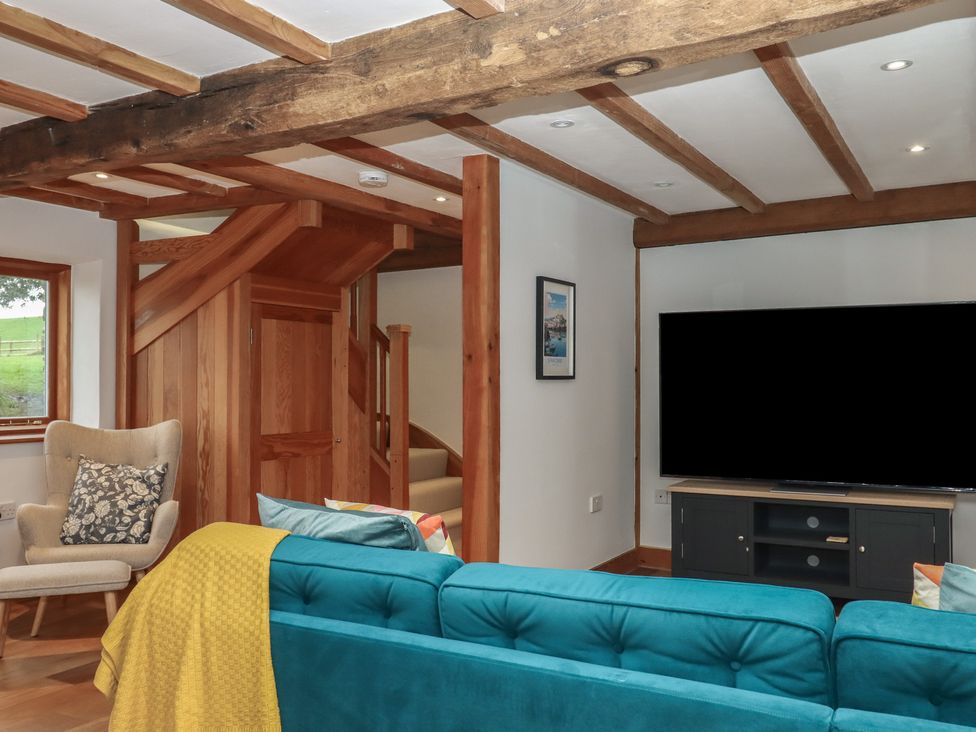 A living room with a television and staircase at Pylemoor Cottage Washfield near Tiverton