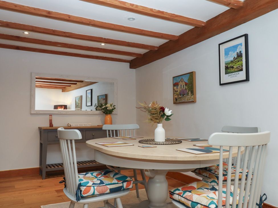 A dining room with a round table and chairs at Pylemoor Cottage in Washfield near Tiverton