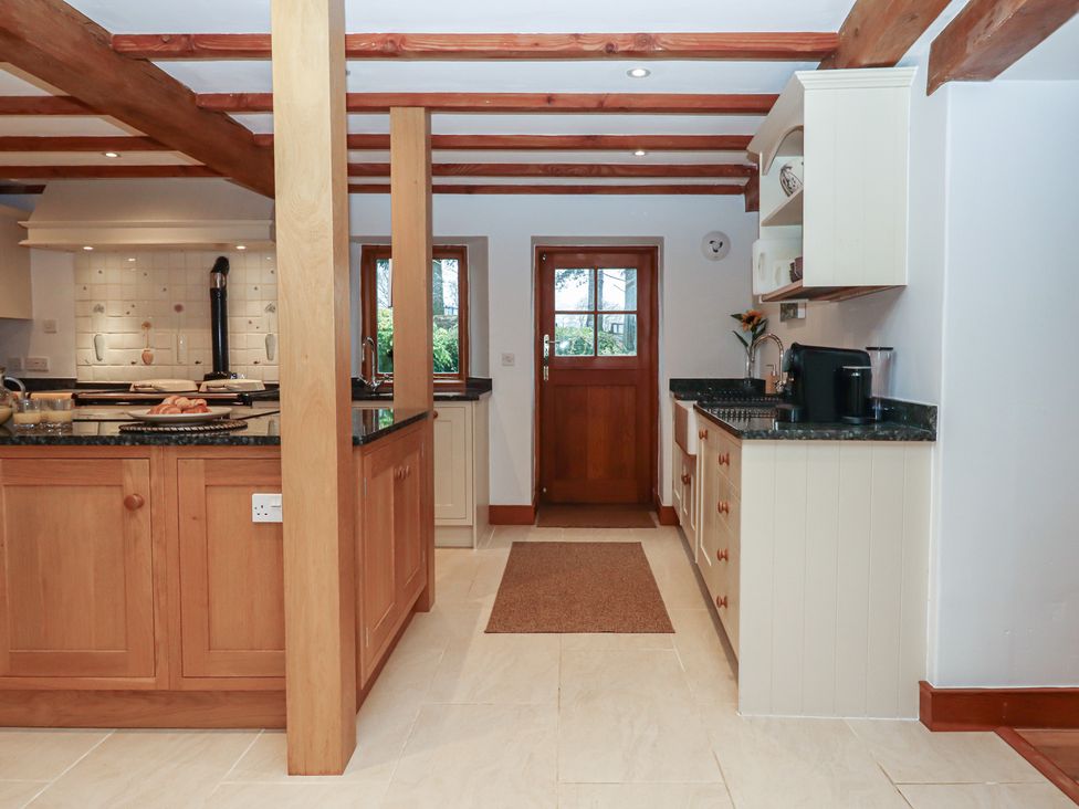 A kitchen with wooden cabinets and a sink at Pylemoor Cottage in Washfield near Tiverton