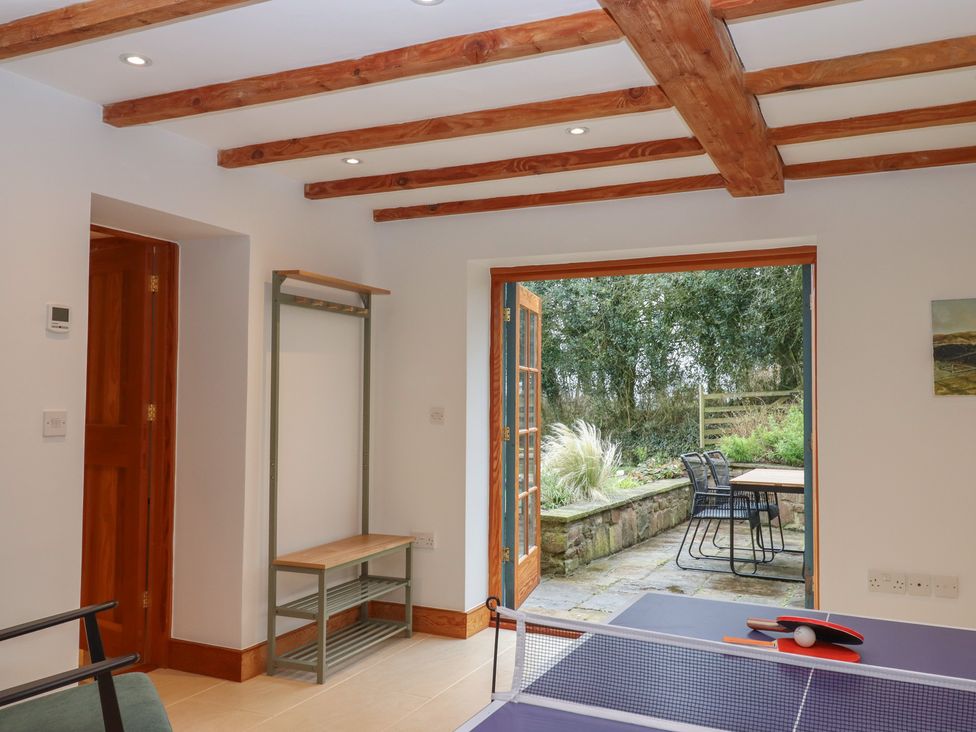 A games room with a table tennis table and door leading to outdoor seating at Pylemoor Cottage Washfield near Tiverton