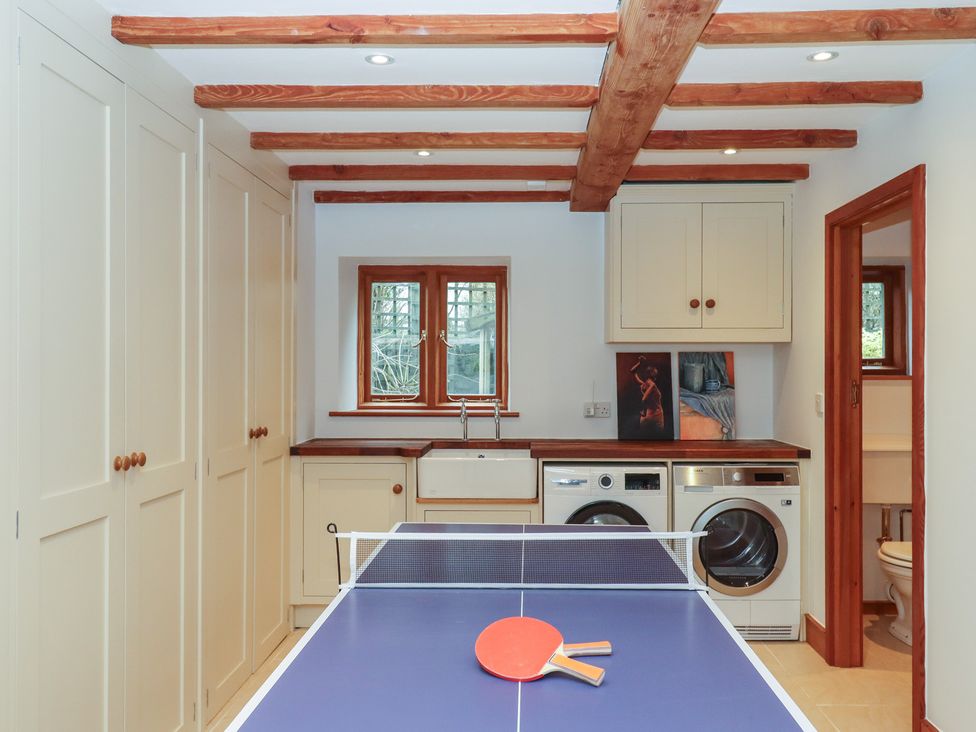A utility room with a ping pong table and laundry machines at Pylemoor Cottage, Washfield near Tiverton