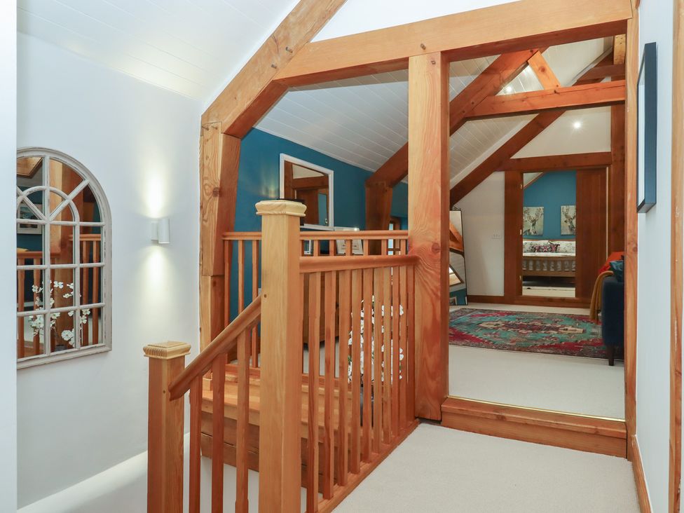 A hallway with a staircase and framed pictures at Pylemoor Cottage Washfield near Tiverton
