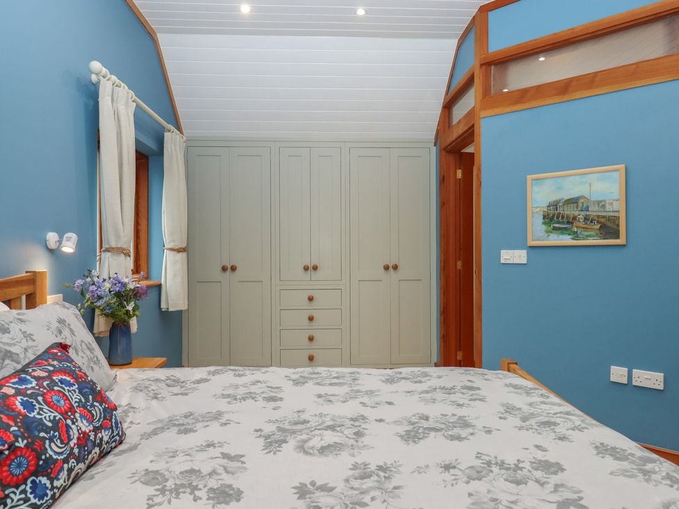 A bedroom with a bed and wardrobe at Pylemoor Cottage in Washfield near Tiverton