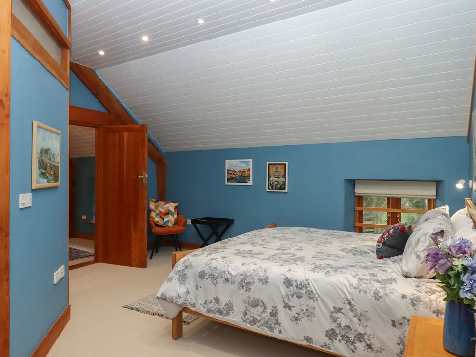 A bedroom with a bed and paintings on the wall at Pylemoor Cottage in Washfield near Tiverton