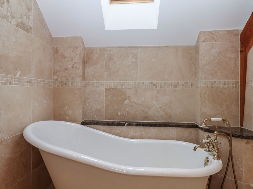 A bathroom with a bathtub and tile walls at Pylemoor Cottage Washfield near Tiverton
