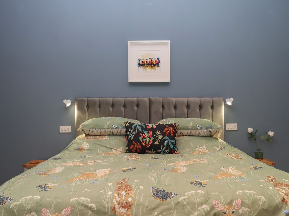 A bedroom with a bed and wall art at Pylemoor Cottage in Washfield near Tiverton